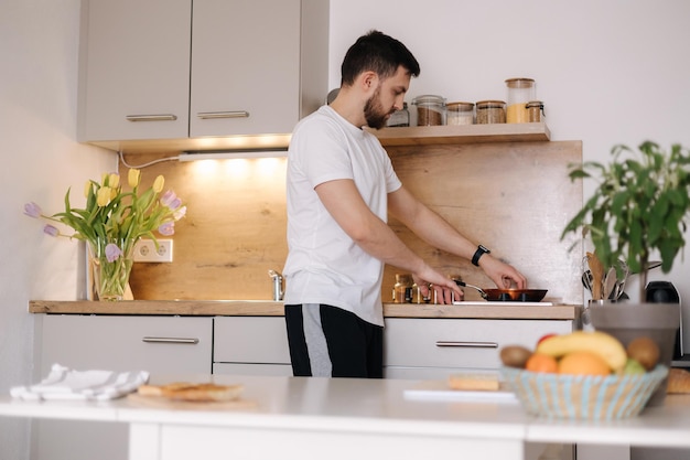 Hombre guapo preparando comida en casa Hombre joven sorprende a su amada mujer y prepara el desayuno en la cocina