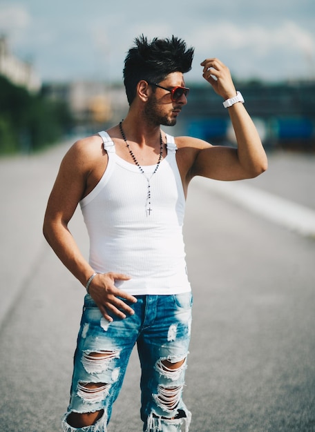 Foto hombre guapo protegiendo los ojos mientras está de pie en la carretera