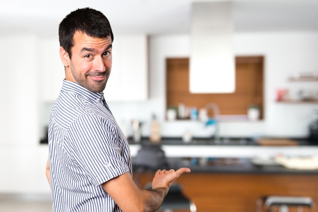 Foto hombre guapo que presenta algo dentro de la casa