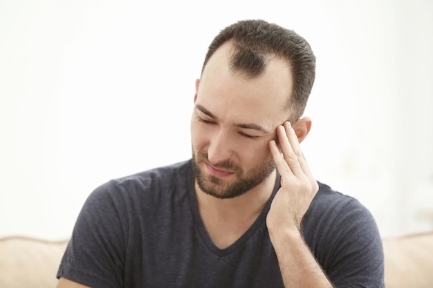 Hombre guapo que sufre de dolor de cabeza en casa