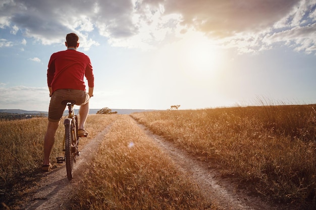 Hombre guapo que viaja con bicicleta en el viajero de estilo de vida activo y saludable al atardecer