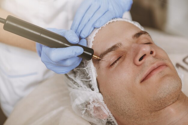 Hombre guapo recibiendo tratamiento facial de cuidado de la piel