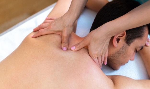 Hombre guapo relajándose y disfrutando de un masaje de espalda de tejido profundo en el salón de spa