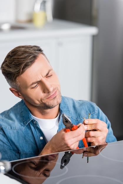 Hombre guapo reparando cables de estufa eléctrica