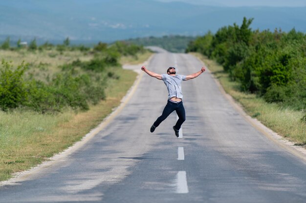 Hombre guapo saltando en la carretera de la calle y divirtiéndose al aire libre