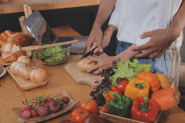 Hombre guapo sentado junto a su esposa en la cocina Una pareja de familia ve las redes sociales navegando por la web mientras están sentados en la mesa de la cocina con una computadora portátil genérica Una pareja trabajando con una laptop en casa