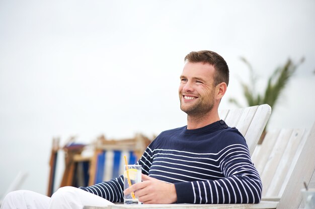 Hombre guapo sentado y sonriendo al aire libre