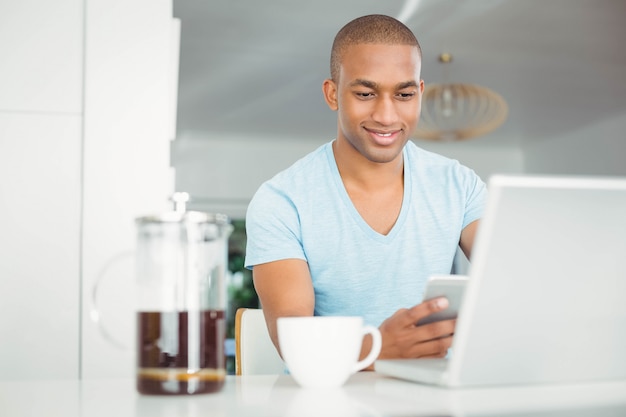 Hombre guapo con smartphone en la cocina