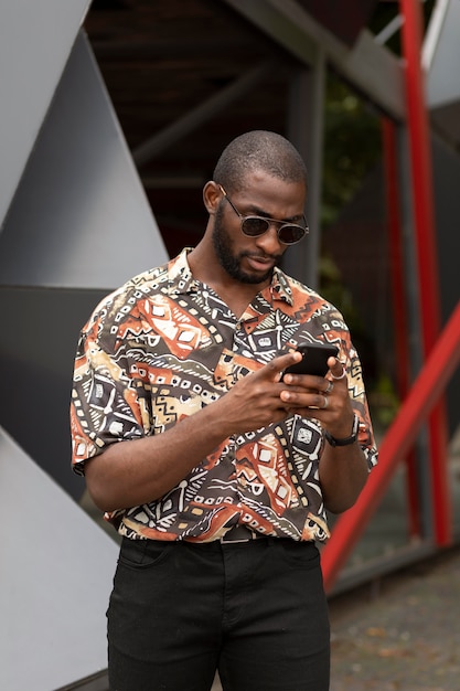 Hombre guapo con smartphone moderno al aire libre