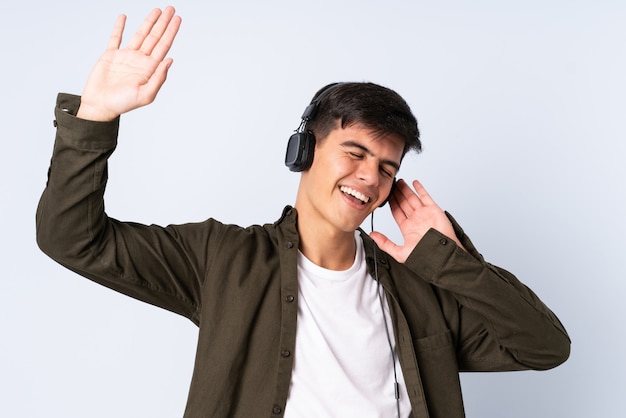 Hombre guapo sobre fondo azul aislado escuchando música y bailando