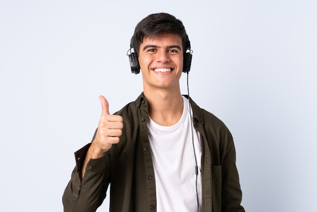 Hombre guapo sobre fondo azul aislado escuchando música y con el pulgar arriba