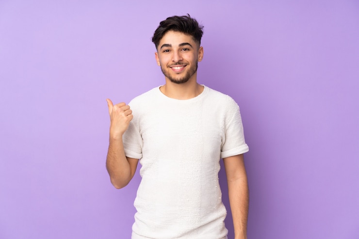 Foto hombre guapo sobre pared aislada apuntando hacia un lado para presentar un producto