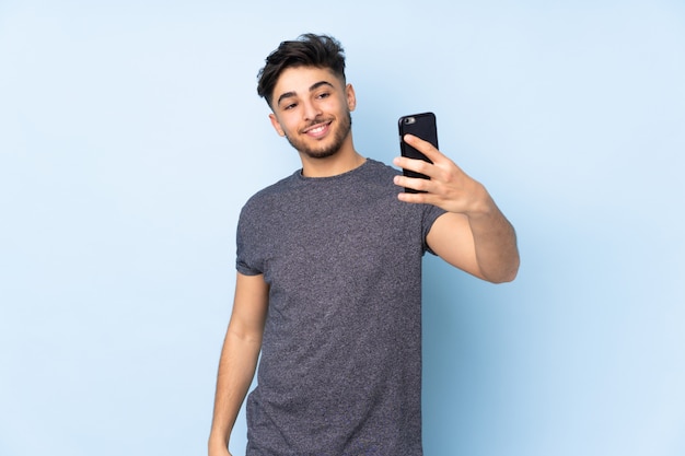 Hombre guapo sobre pared aislada haciendo un selfie