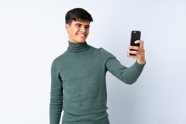 Hombre guapo sobre pared azul haciendo una selfie