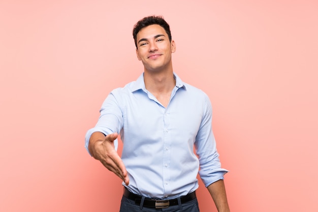 Hombre guapo sobre rosa estrechándose las manos para cerrar un buen trato