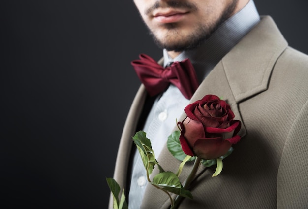 Hombre guapo con una sola rosa roja