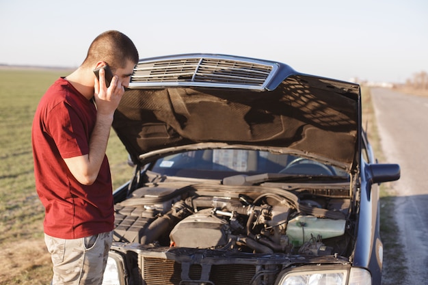 Foto hombre guapo está solo cerca del coche roto