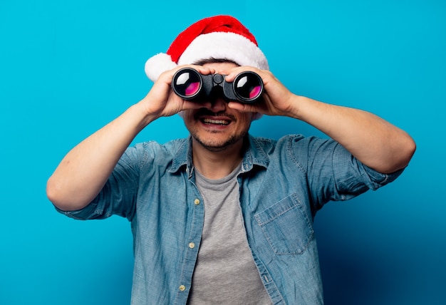 Hombre guapo con sombrero de Navidad con binoculares