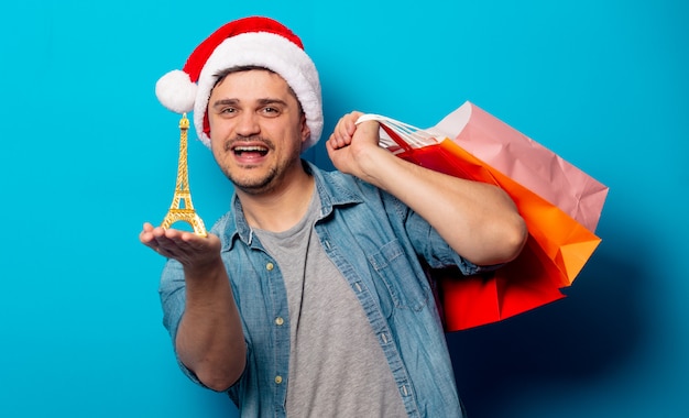 Hombre guapo con sombrero de Navidad con bolsas de compras y la Torre Eiffel