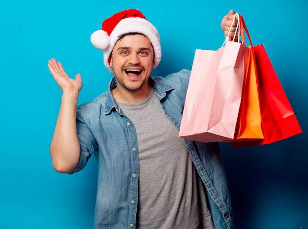 Hombre guapo con sombrero de Navidad con bolsas de compras