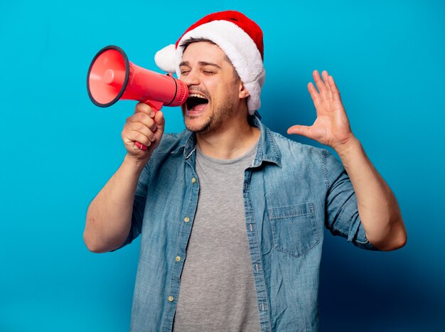 Hombre guapo con sombrero de Navidad con hailer ruidoso