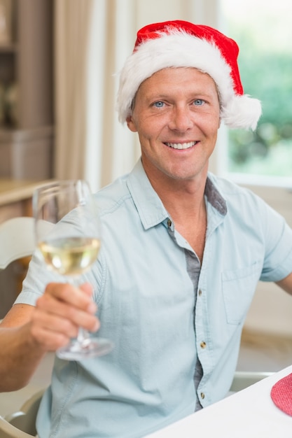 Hombre guapo en sombrero de santa brindando con vino blanco