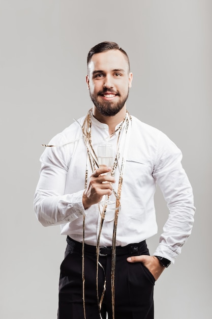 Hombre guapo sonríe y sostiene una copa de champán sobre un fondo blanco. Tiempo de fiesta .