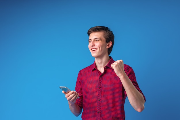 Hombre guapo sonriente positivo con un teléfono móvil