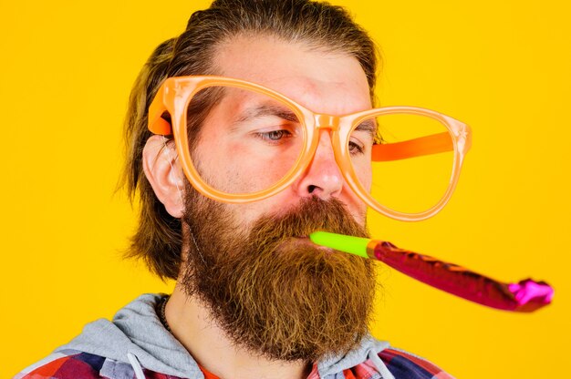 Hombre guapo con soplador de cuerno de fiesta. Concepto de personas, cumpleaños y celebración.