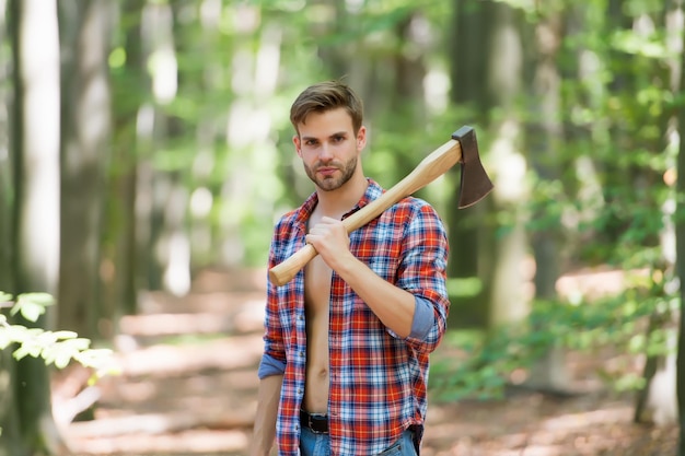 Hombre guapo sostenga hacha en actividad forestal