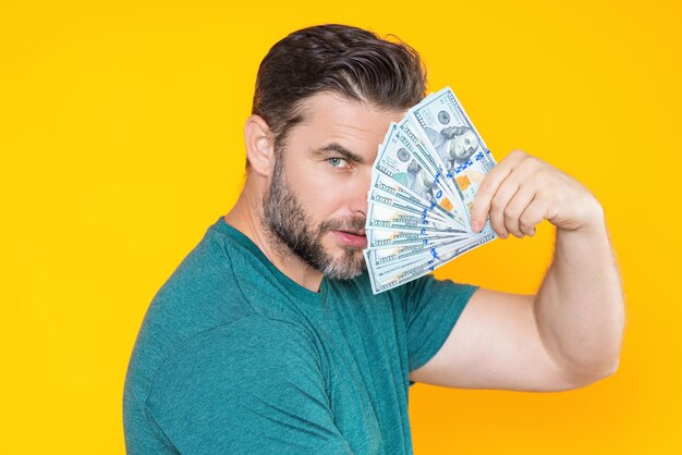 Foto hombre guapo sosteniendo dinero aislado sobre dinero de estudio gris en billetes de dólar montón de finanzas en efectivo