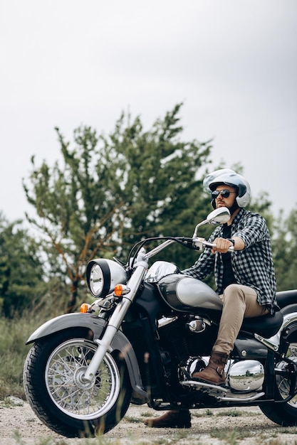 Hombre guapo con su moto en cantera de arena