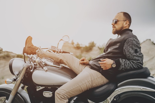 Hombre guapo con su moto en cantera de arena