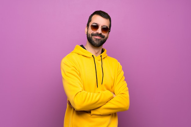 Hombre guapo con sudadera amarilla con gafas y sonriendo