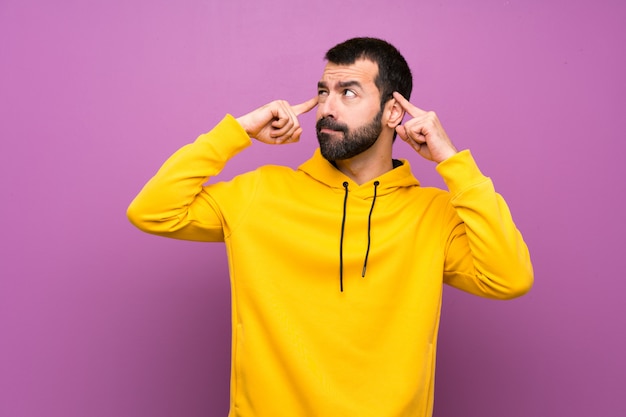 Hombre guapo con sudadera amarilla teniendo dudas y pensando