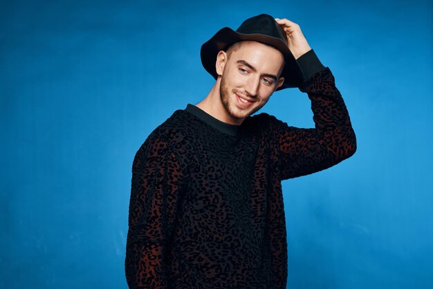 Hombre guapo en suéter negro posando sobre fondo azul ropa moderna