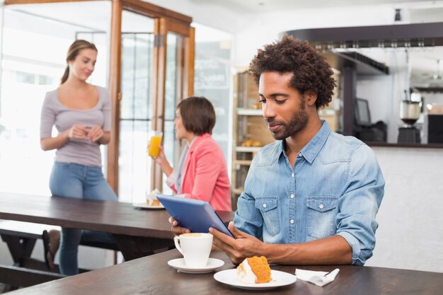 Hombre guapo con tableta mientras toma un café