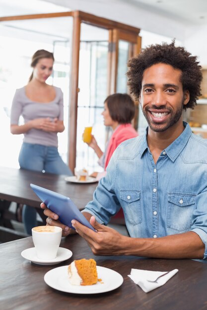 Hombre guapo con tableta mientras toma un café