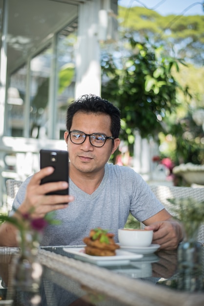 Hombre guapo con teléfono móvil en el café