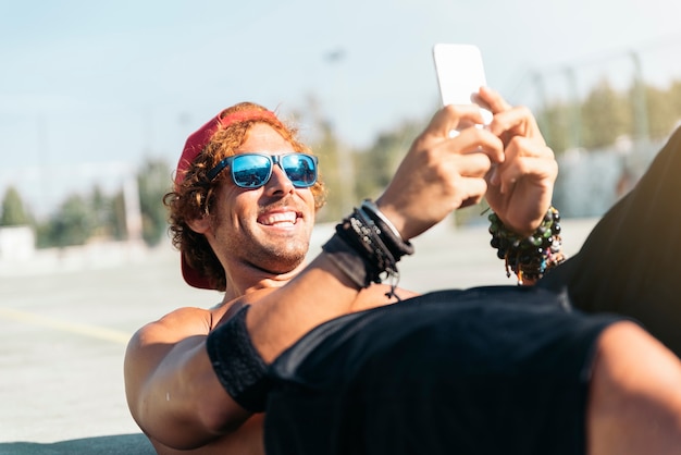 Hombre guapo con un teléfono móvil en una cancha de baloncesto de la calle