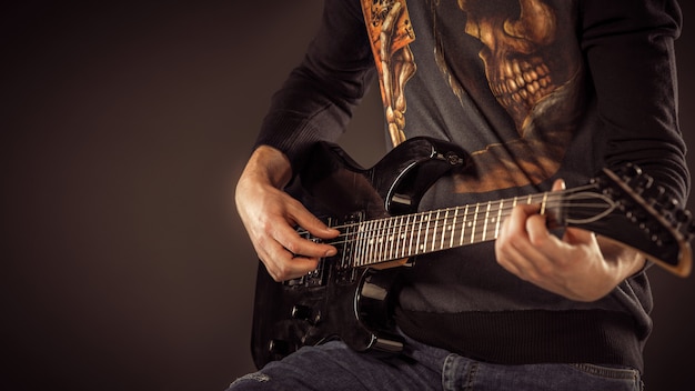 Hombre guapo tocando la guitarra electro, tiro