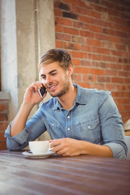 Hombre guapo tomando un café y llamando