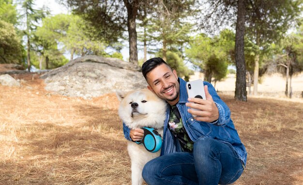 Hombre guapo tomando fotografías con su perro