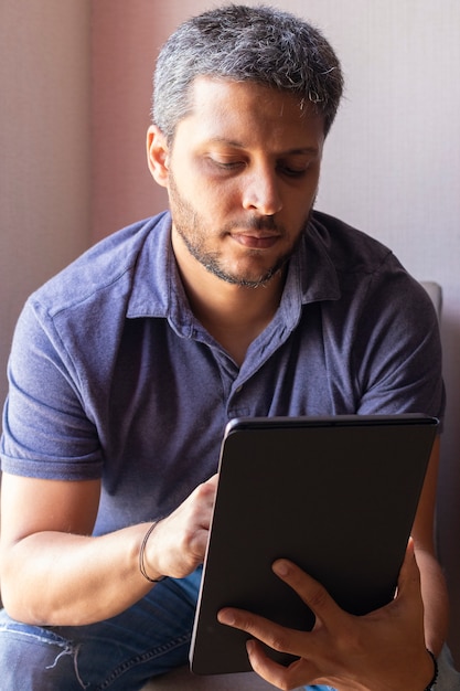 Hombre guapo trabajando en casa con su tableta