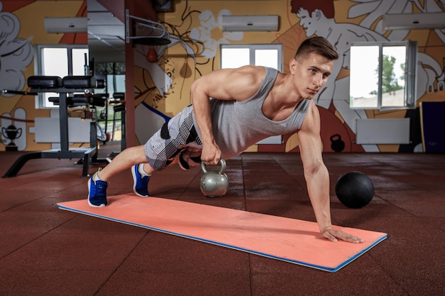 Hombre guapo trabajando flexiones en el gimnasio. Ejercicios deportivos