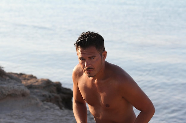 Hombre guapo con traje de baño está disfrutando en la playa al atardecer Apulia Salento Italia