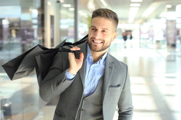 Hombre guapo en traje con bolsas de la compra.