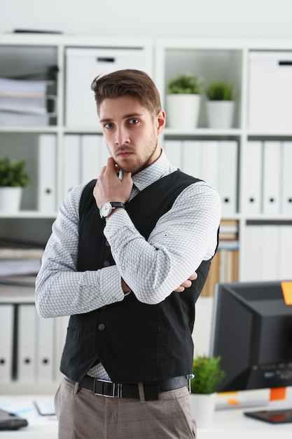 Hombre guapo en traje y corbata de pie en la oficina