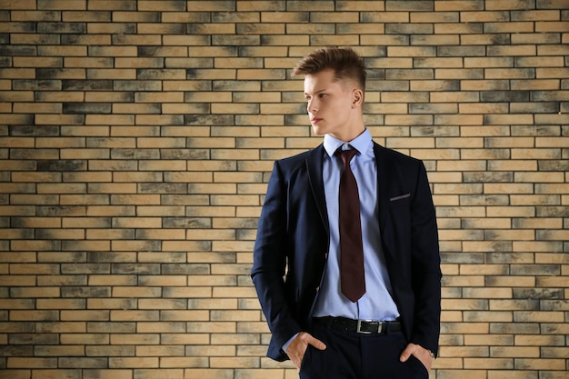 Hombre guapo en traje formal contra la pared de ladrillo