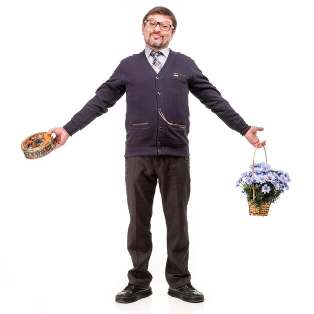 Un hombre guapo con traje y gafas con dulces y flores. Fondo blanco.